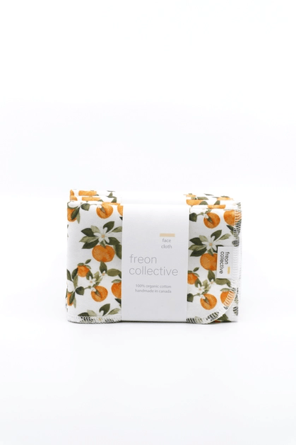 Folded face cloth in Clementine print, with various small clementine fruits, white flowers and green leaves