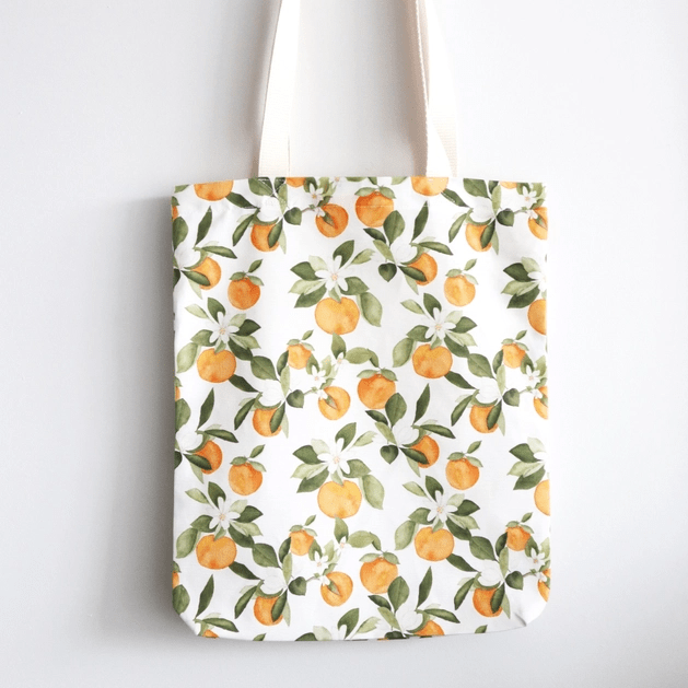 Zoom of tote bag in Clementine print, with various small clementine fruits, white flowers and green leaves