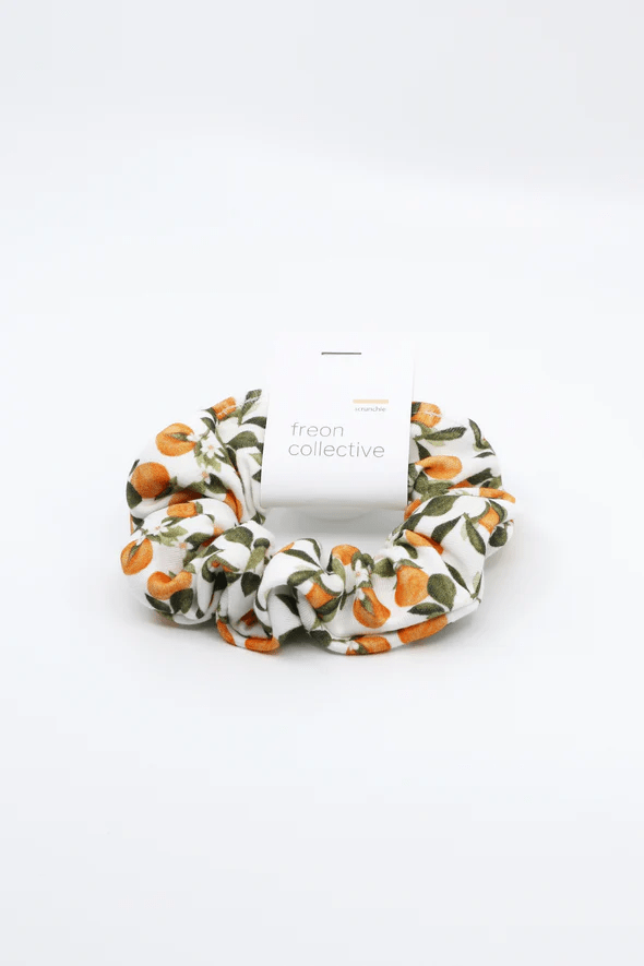 Scrunchie in Clementine print, with various small clementine fruits, white flowers and green leaves