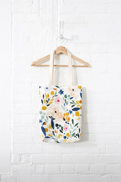 Tote bag in Sierra Florals, a colourful floral print, hung in wood hanger